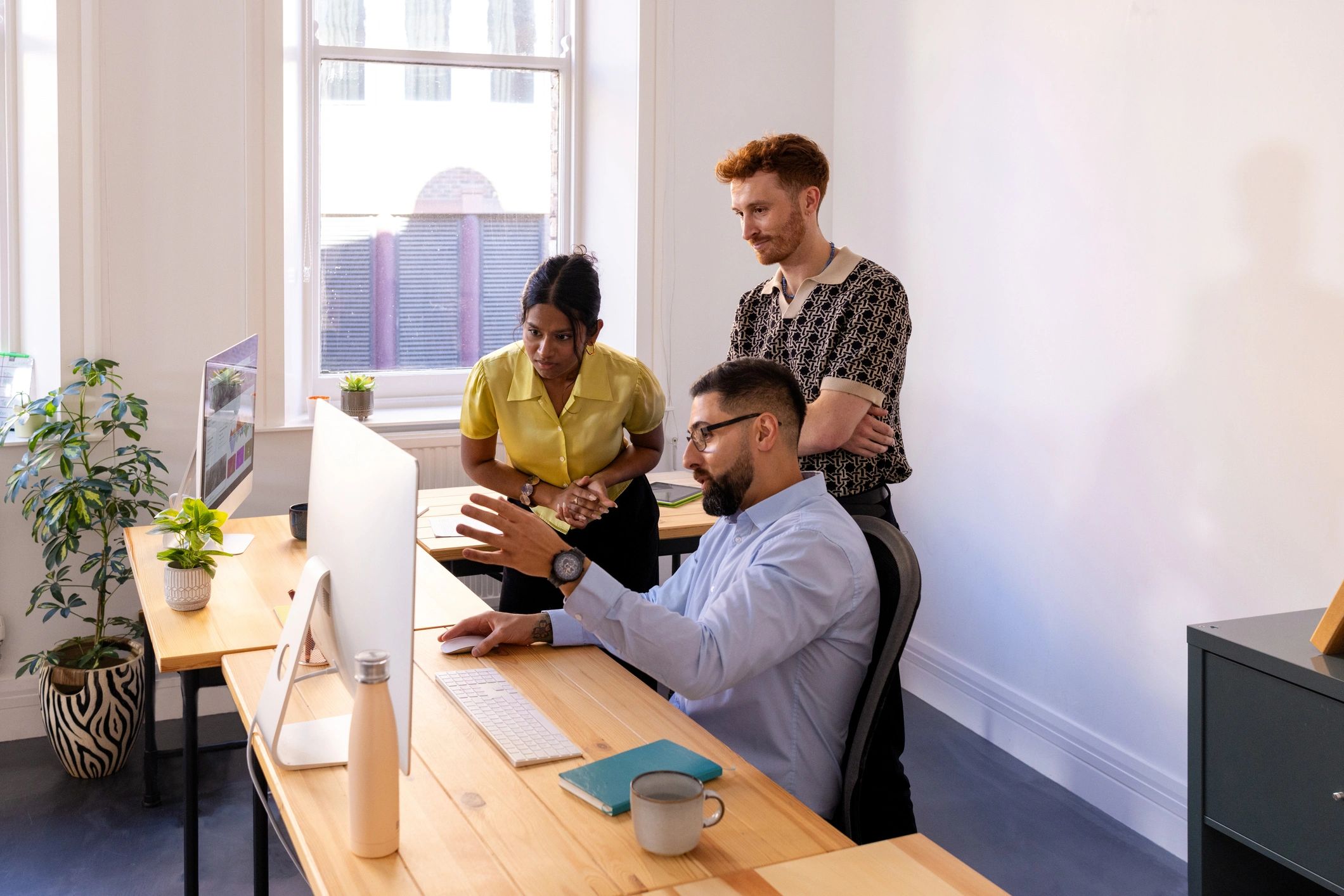 Creative agency team collaborating around a computer